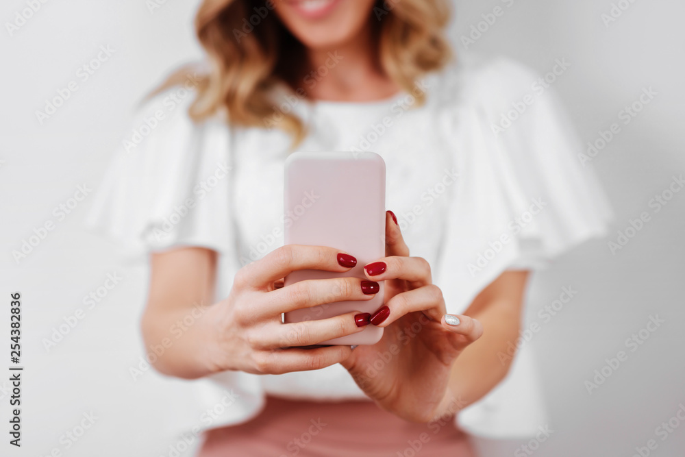 Portrait of a smiling casual woman holding smartphone over white background Portrait of a smiling casual woman holding smartphone over white background
