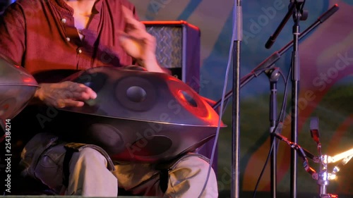 Man playing tank drum or hang on stage of ethnic open air concert. Relaxation, folk, meditative and traditional ethnic music concept photo