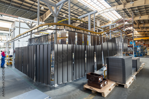 Powder coating line. Metal panels are suspended on an overhead conveyor line.