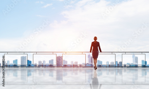 Sunrise above skyscrapers and businesswoman facing new day