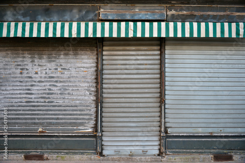 Old store. Ancient storefront with metallic closed curtains. Abandoned shop business.