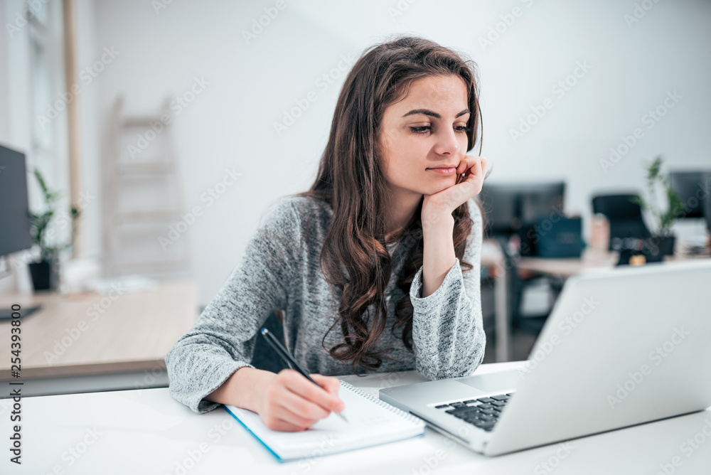 Girl looking at laptop and taking notes. Business, education and people concept. Girl looking at laptop and taking notes. Business, education and people concept.