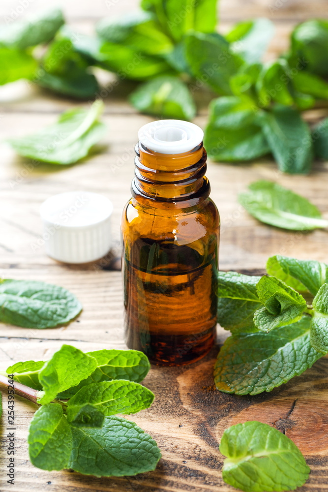 Essential aroma oil with peppermint on wooden background. Selective focus, copy space. Essential aroma oil with peppermint on wooden background. Selective focus, copy space.