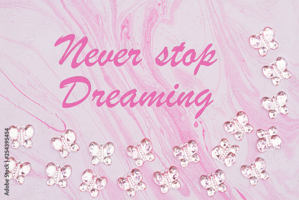 Never Stop Dreaming message with pink glass butterflies on pink watercolor paper