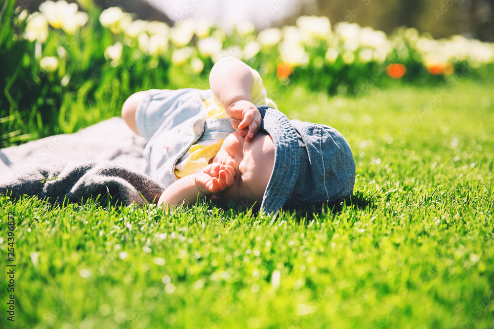Baby in green grass of tulip field at springtime Baby in green grass of tulip field at springtime