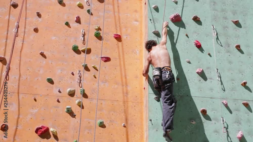 man climber is climbing on the outdoors climbing gym at sunny summer day. man climber is climbing on the outdoors climbing gym at sunny summer day.