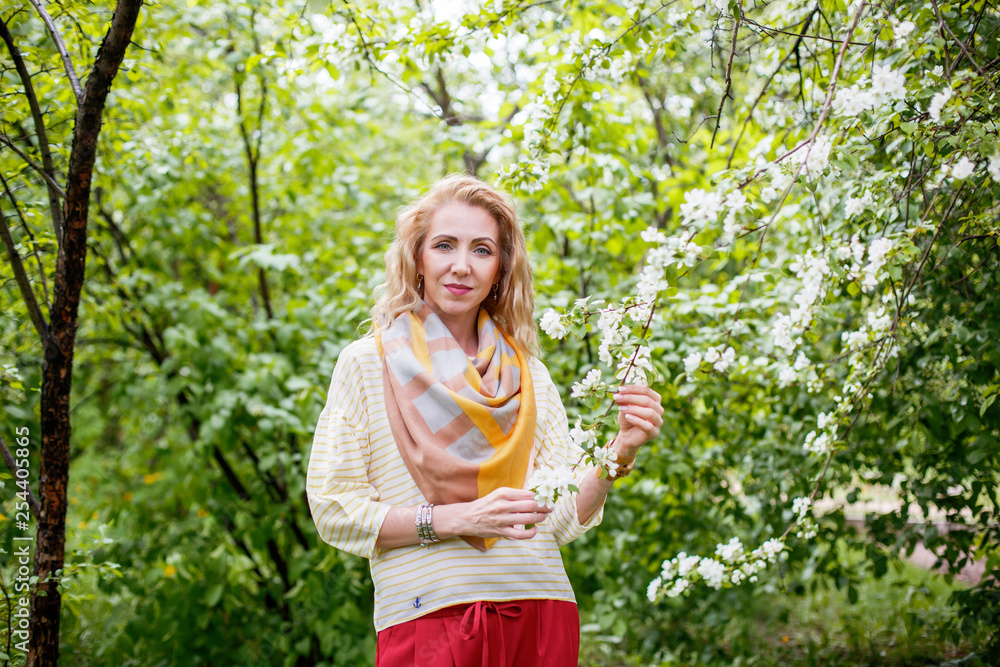 Woman in a light jumper on the street in spring in blooming apple trees Woman in a light jumper on the street in spring in blooming apple trees