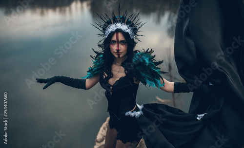 Schilderij op canvas A woman in the image of a fairy and a sorceress standing over a lake in a black dress and a crown