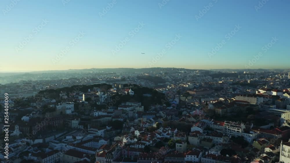 Aerial view; drone flight forward to the ancient building with brown rooftops; sunset time in Lisbon; beautiful winter evening in Portuguese capital; Alfama oldest historic district; view from above Aerial view; drone flight forward to the ancient building with brown rooftops; sunset time in Lisbon; beautiful winter evening in Portuguese capital; Alfama oldest historic district; view from above