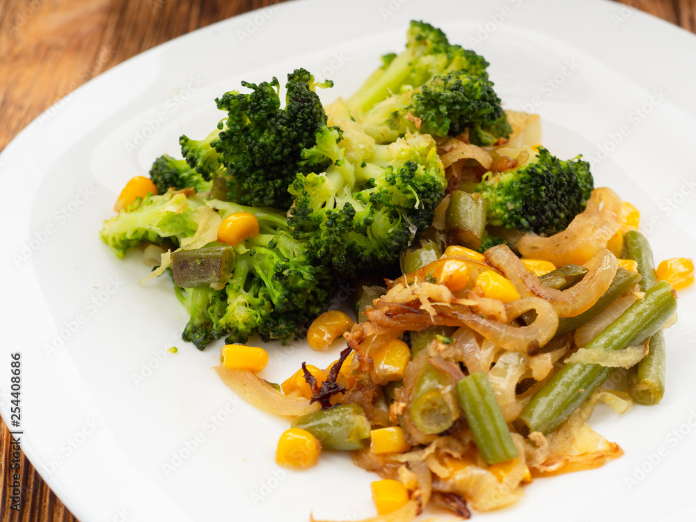 cooked vegetables broccoli, carrots, green beans, corn on a white plate. macro cooked vegetables broccoli, carrots, green beans, corn on a white plate. macro