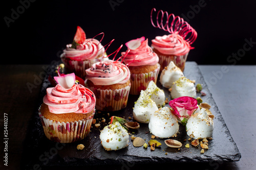 Cupcakes with pink cream, meringues sprinkled with nuts.