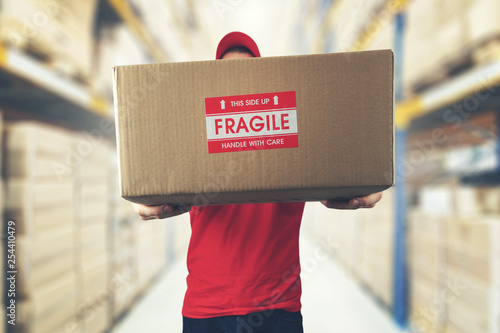 logistics warehouse worker holding package with fragile items photo