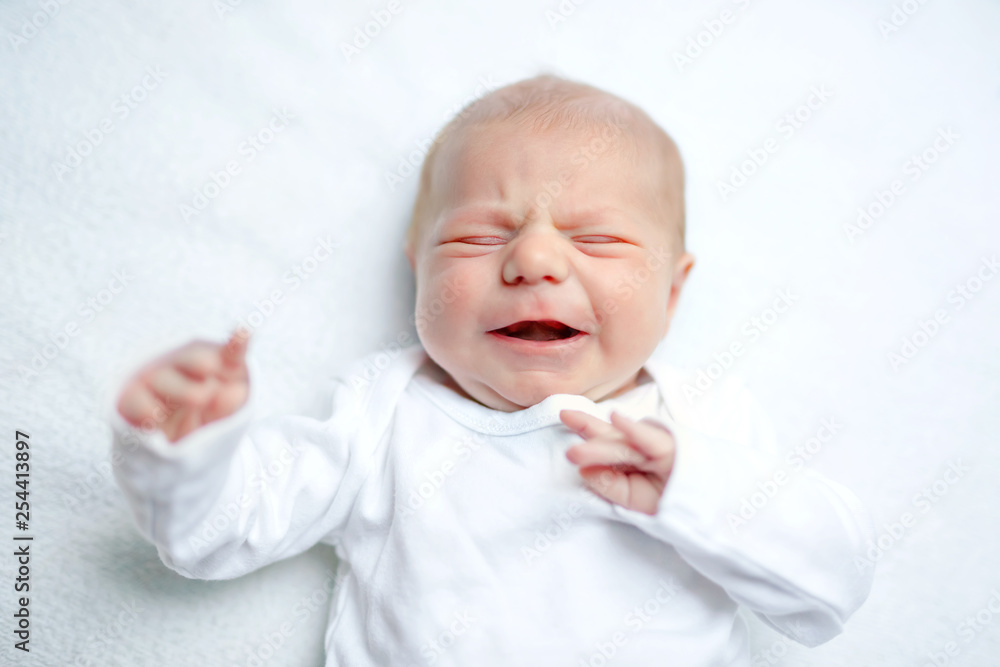 Crying newborn baby on changing table. Cute little girl or boy two weeks old. Dry and healthy body and skin concept. Baby nursery. Crying newborn baby on changing table. Cute little girl or boy two weeks old. Dry and healthy body and skin concept. Baby nursery.