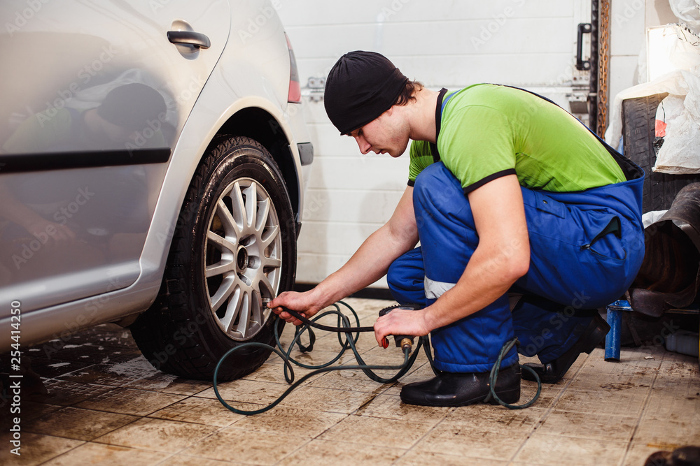 car repair at a service station. A young man checks the tire pressure car repair at a service station. A young man checks the tire pressure