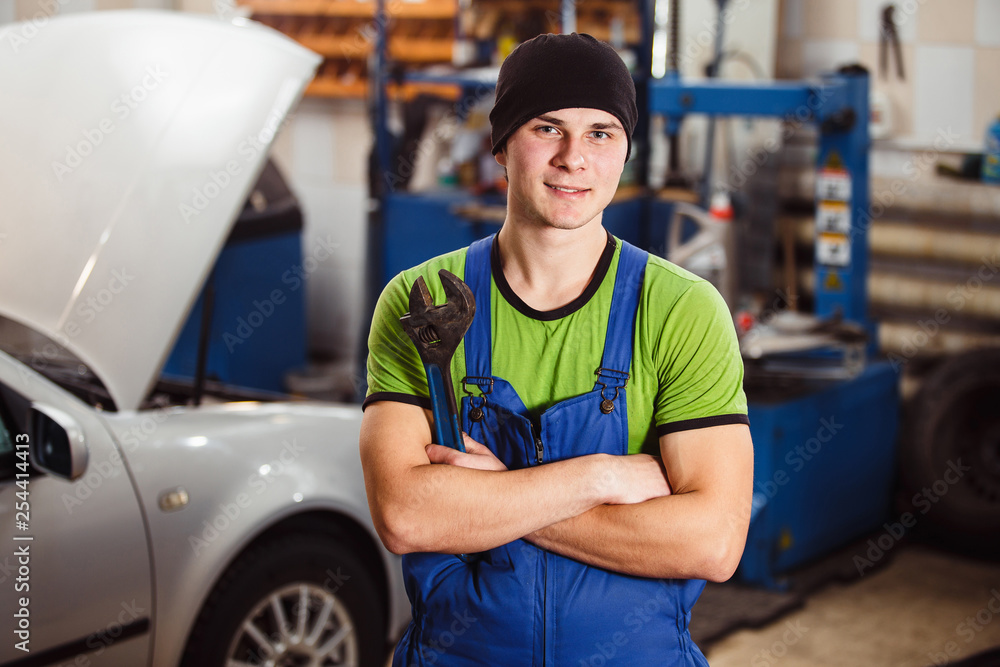 A young man posing with a swivel key. Car repair at a service station A young man posing with a swivel key. Car repair at a service station