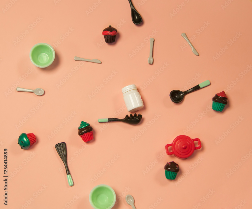 flat lay image of plastic toy tableware with cakes on pastel pink background flat lay image of plastic toy tableware with cakes on pastel pink background