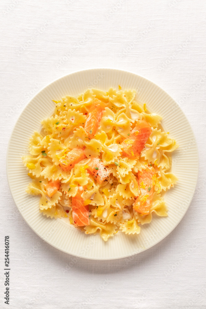 Smoked salmon with bowtie pasta. Farfalle with salmon and a cream sauce, shot from above on a white linen tablecloth with copy space