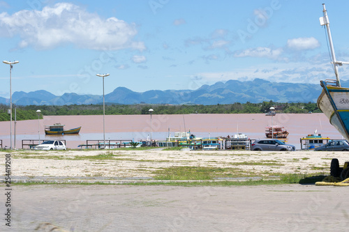 Scene of a road trip in the Espirito Santo state in Brazil. A river with a reddish colour water and high blue mountains in the background