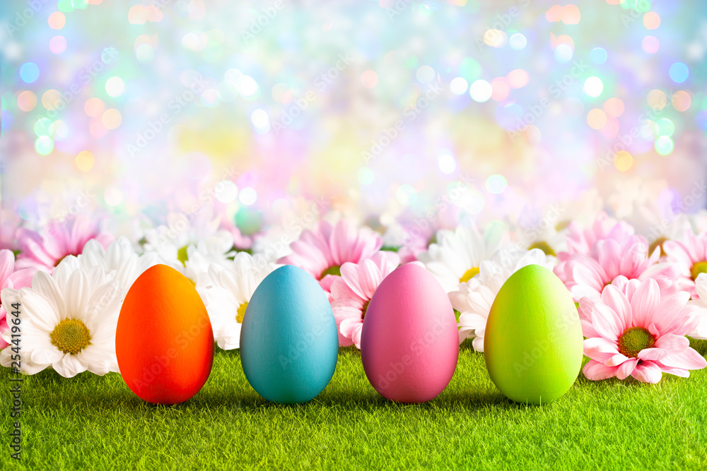 Pink and white flowers and Easter eggs on the grass and colorful abstract background