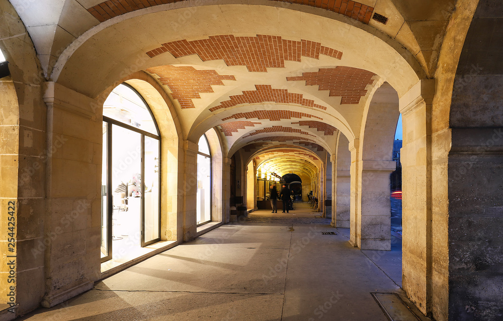 The arcades of place des Vosges in Paris , France.