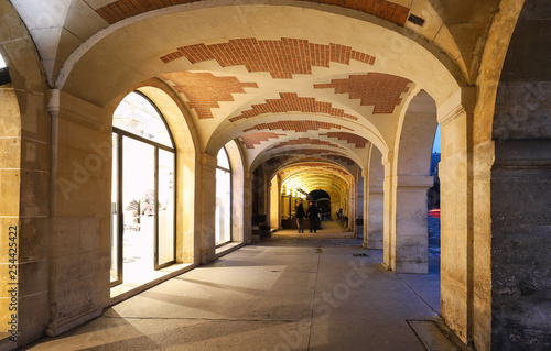 The arcades of place des Vosges in Paris , France.