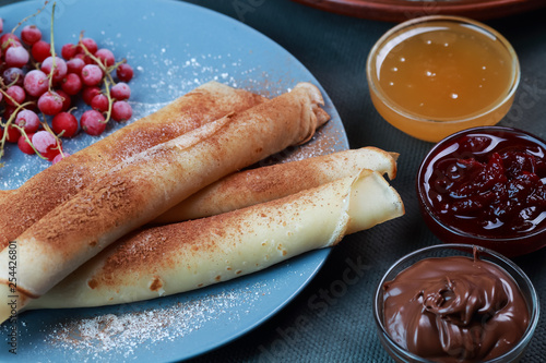pancakes with berries, jam, honey and chocolate, sprinkled with powdered sugar and cinnamon