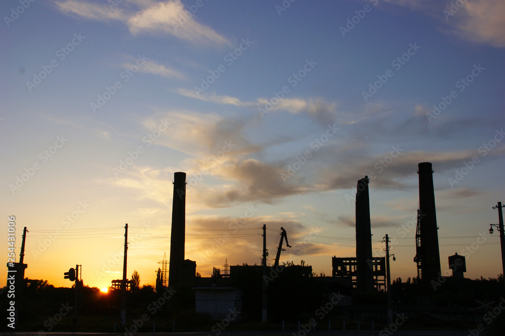 Silhouette of an abandoned mining processing factory with sunset in background.
