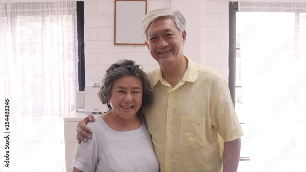 Asian elderly couple feeling happy smiling and looking to camera while relax in living room at home. Enjoying time lifestyle senior family at home concept. Portrait looking at camera. Asian elderly couple feeling happy smiling and looking to camera while relax in living room at home. Enjoying time lifestyle senior family at home concept. Portrait looking at camera.