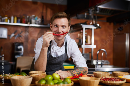 Portrait of professional chef holding red chili pepper and looking at camera, copy space