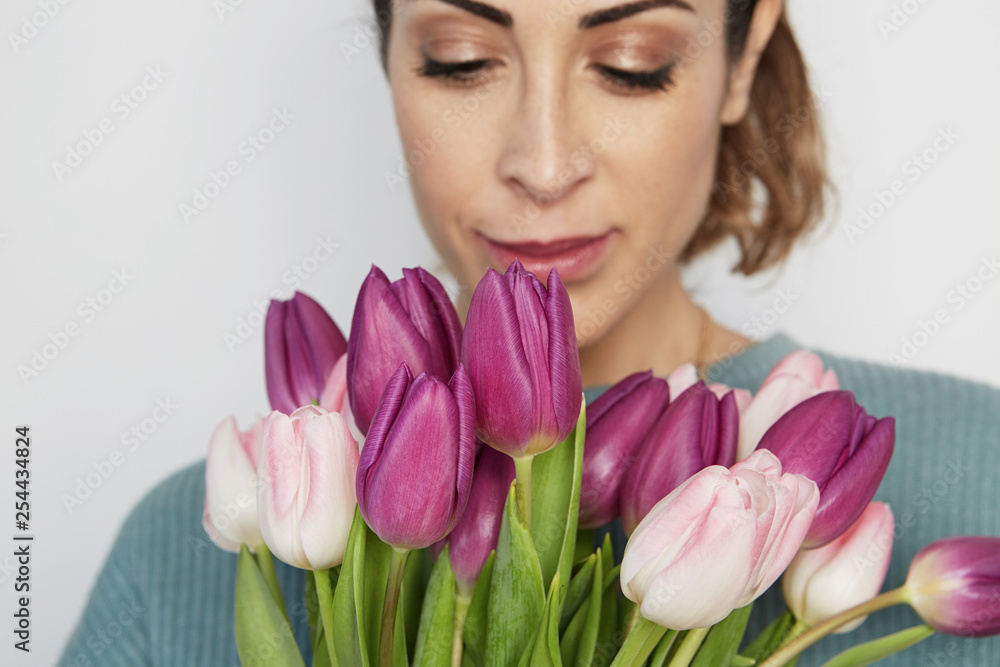 Portrait of a cheerful young girl holding pink tulips bouquet isolated over white background. Portrait of a cheerful young girl holding pink tulips bouquet isolated over white background.