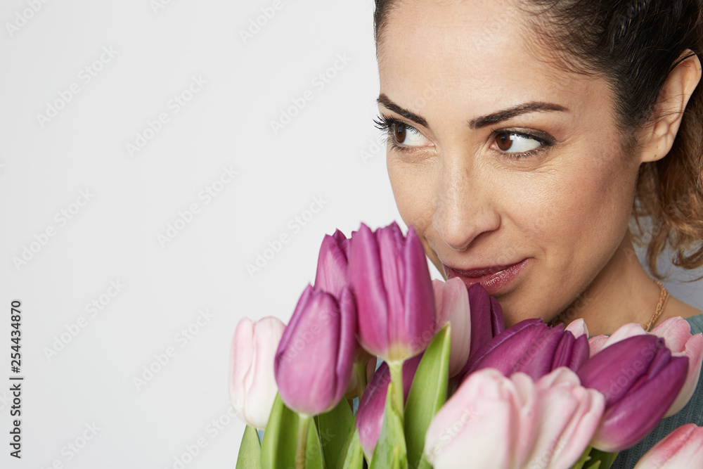 Portrait of a cheerful young girl holding pink tulips bouquet isolated over white background. Portrait of a cheerful young girl holding pink tulips bouquet isolated over white background.