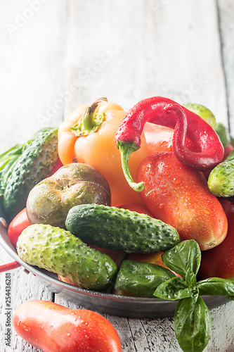 Fresh organic vegetables from the garden in metal pan over rustic wooden background