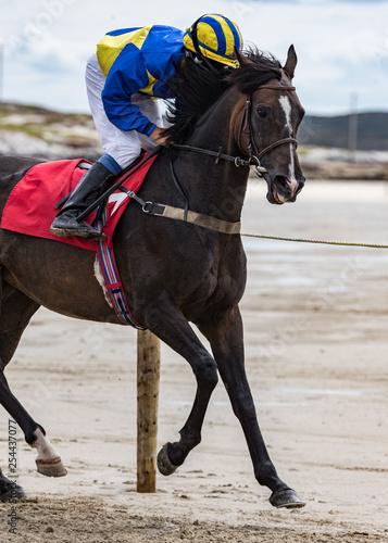 Jockey and race horse running on the beach
