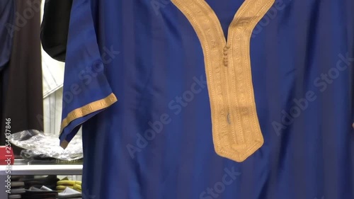 Morocco, North Africa. Moroccan market seller showing traditional Berber men's robe gandoura or gandora, close up shot.