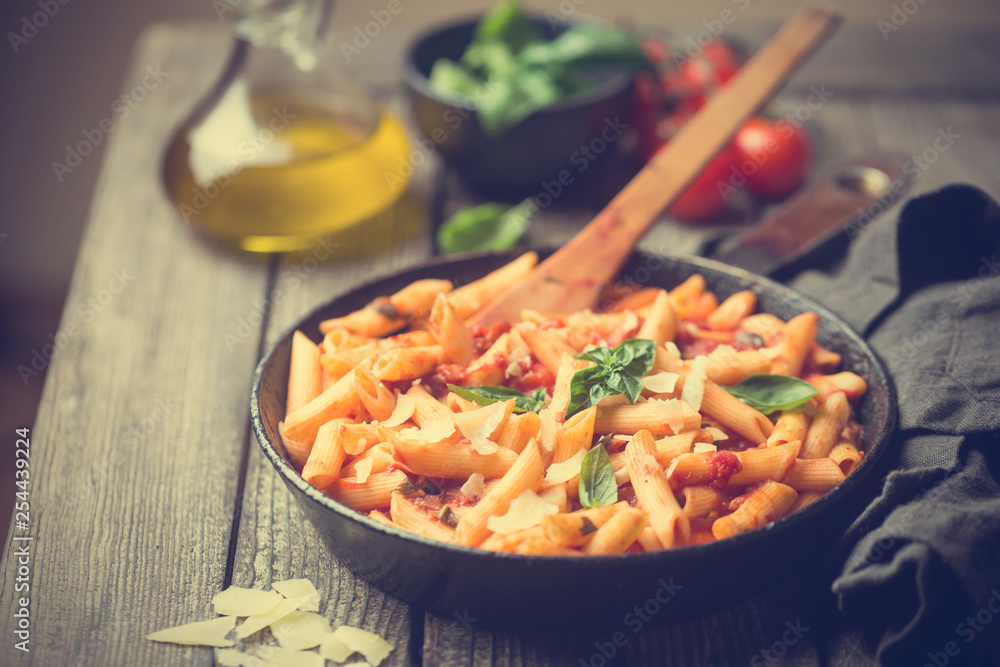 Penne pasta in tomato sauce and cheese decorated with basil on a wooden background Penne pasta in tomato sauce and cheese decorated with basil on a wooden background
