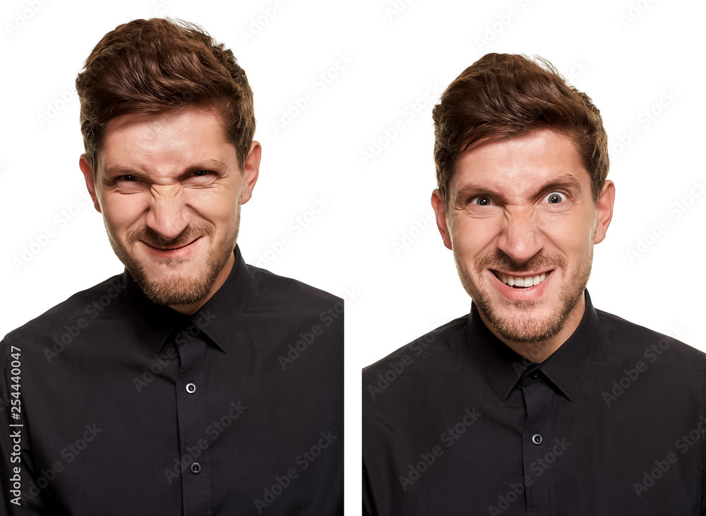 Handsome man in a black shirt makes faces, standing against a white background Handsome man in a black shirt makes faces, standing against a white background