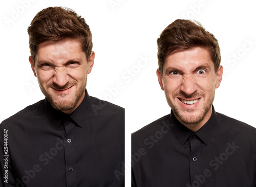 Handsome man in a black shirt makes faces, standing against a white background