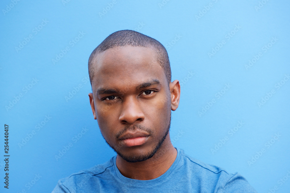 Close up cool young black man against blue background Close up cool young black man against blue background