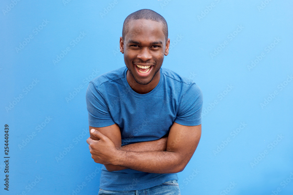 handsome young african american man laughing with arms crossed - obrazy, fototapety, plakaty 