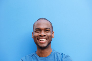 Close up happy young black man against blue background