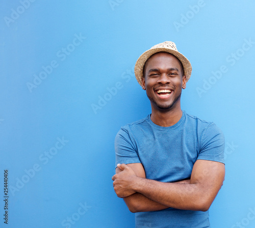 handsome young black guy with hat smiling against blue background