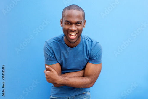 handsome young african american man laughing with arms crossed