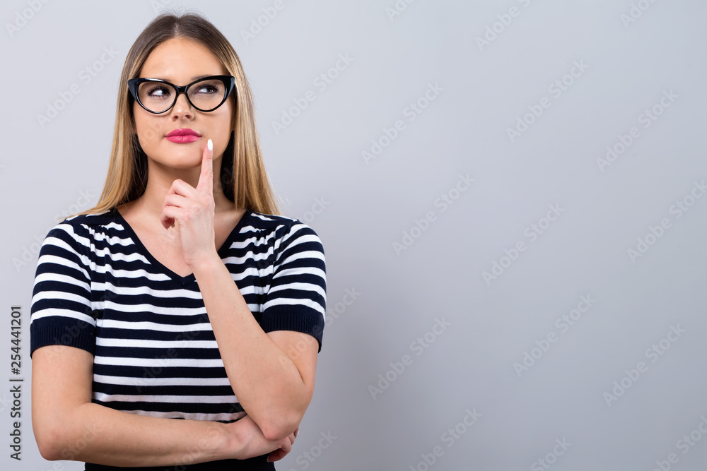 Young woman in a thoughtful pose on a gray background Young woman in a thoughtful pose on a gray background