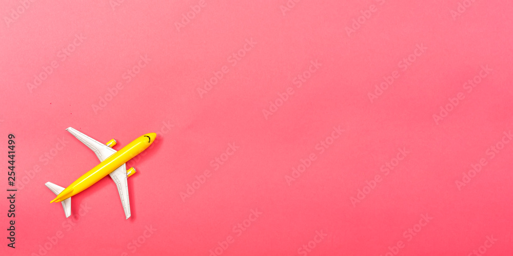 A toy airplane on a pink paper background