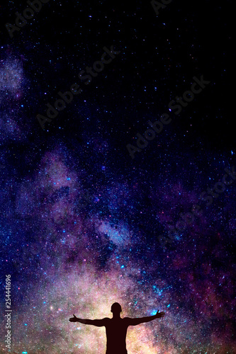 dark silhouette of man with opened hands under beautiful bright night sky with Milky way. Space concept for postcard, wallpaper or design, Vertical with copy space background for text