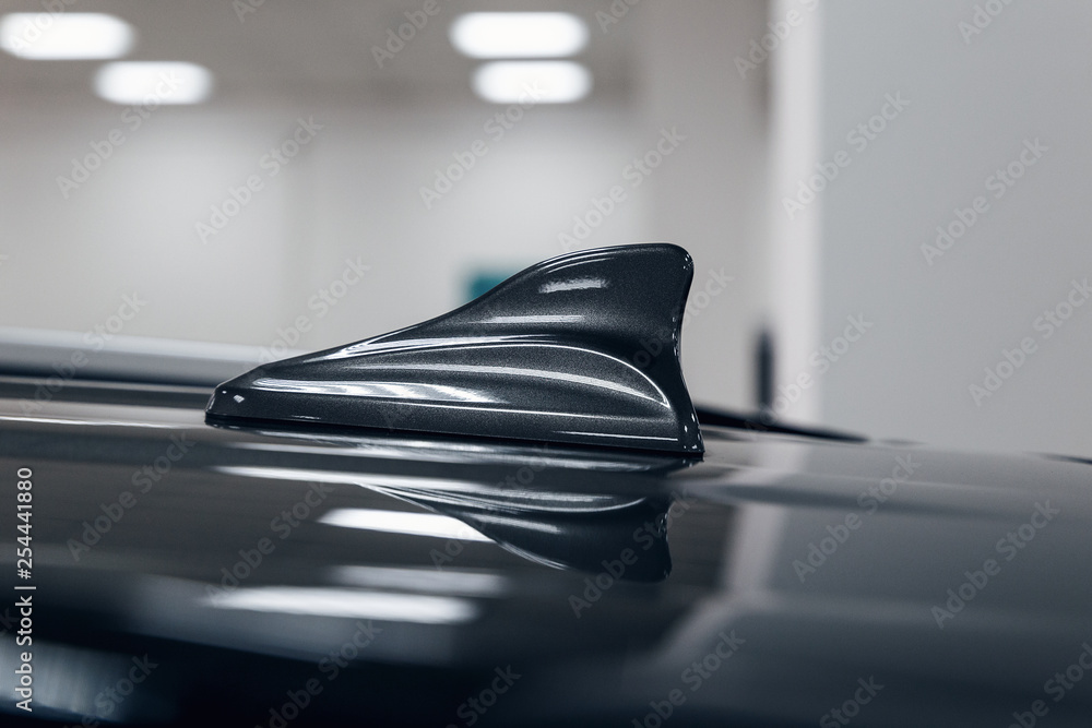 Close-up GPS antenna shark fin shape on a roof of car for radio navigation system. Antenna shark fin on blurry background. Car detail Close-up GPS antenna shark fin shape on a roof of car for radio navigation system. Antenna shark fin on blurry background. Car detail