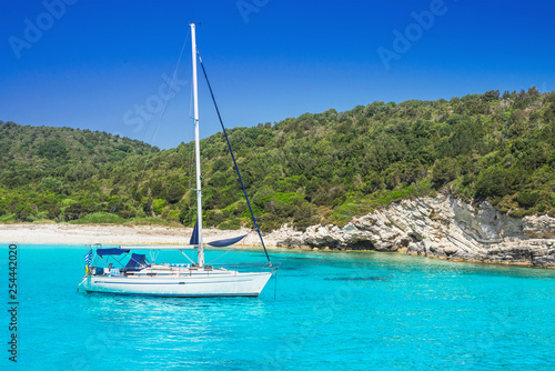 Beautiful bay with sailing boat, Greece. Vacations, travel and active lifestyle concept. Greek sandy beach at background