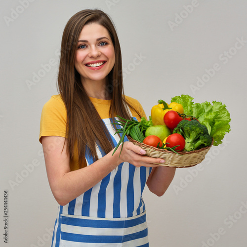 Smiling woman wearing striped apron holding vegetabless. photo