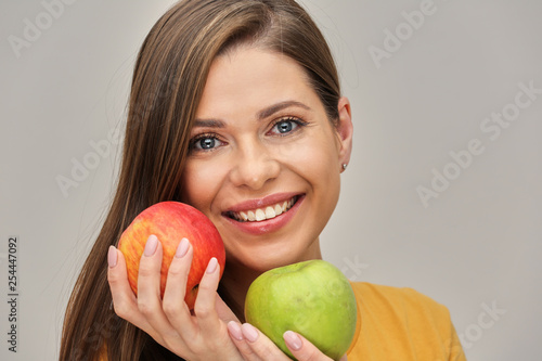 woman smiling with healthy teeth holding two apples. photo