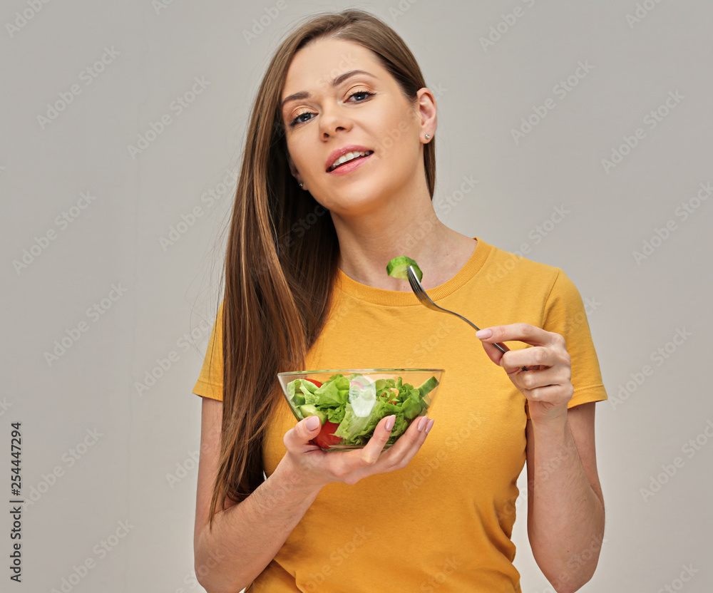woman dressed in yellow eating salad from glass bowl using fork woman dressed in yellow eating salad from glass bowl using fork